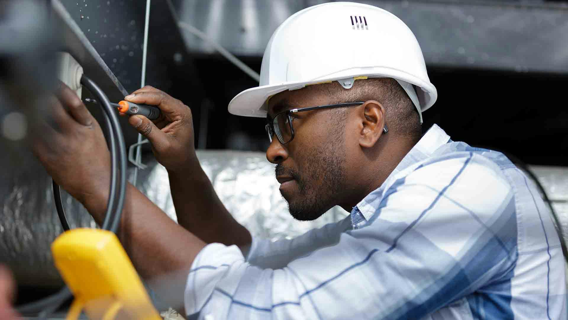 Electrician using digital multi-meter to check a circuit breaker